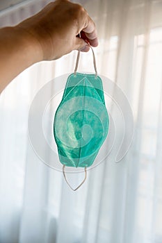 Protective face mask hang on hand. Typical 3-ply surgical mask to cover the mouth and nose. Procedure mask from bacteria. Protecti