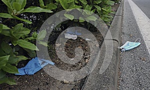 Protective face mask isolated and latex gloves thrown  on an  urban road.