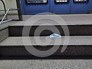 Protective face mask isolated lying on the  ground at the entrance of a building.