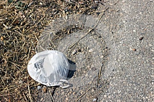 Protective face mask thrown to the ground after use. Consequences of coronavirus pandemic.