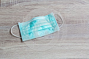 Protective face mask on wood table. Typical 3-ply surgical mask to cover the mouth and nose. Procedure mask from bacteria.