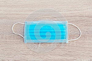 Protective face mask on wood table. Typical 3-ply surgical mask to cover the mouth and nose. Procedure mask from bacteria. Protect