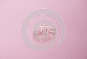 Protective glasses lying on a pink background.