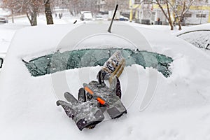 Protective gloves and brush on the snow cowered car rear window