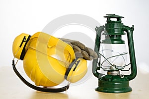 Protective helmet and oil lamp on a wooden table. Safety and health protection accessories for construction workers.