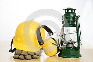 Protective helmet and oil lamp on a wooden table. Safety and health protection accessories for construction workers.