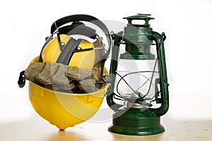 Protective helmet and oil lamp on a wooden table. Safety and health protection accessories for construction workers.