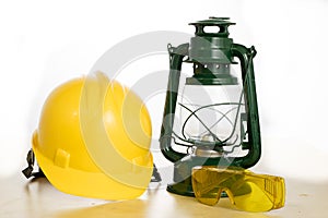 Protective helmet and oil lamp on a wooden table. Safety and health protection accessories for construction workers.