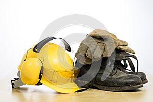 Protective helmet and work boots on a wooden table. Safety and h