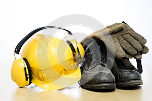 Protective helmet and work boots on a wooden table. Safety and h