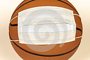 Protective mask on a basketball on a light background. The concept of sporting events during the COVID-19 pandemic