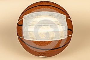 Protective mask on a basketball on a light background. The concept of sporting events during the COVID-19 pandemic