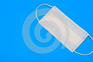 Protective medical disposable mask. White face mask, protection against viruses and bacteria, on a blue background, for quarantine