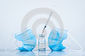 Protective medical mask, a bottle with medicine and a syringe on a blue background. Virus protection concept. Copy space