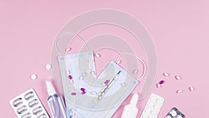 Protective medicine mask, antiseptic thermometer and pills on pink background, flat lay. Concept of doctor table and health care