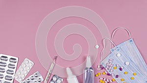 Protective medicine mask, antiseptic thermometer and pills on pink background, flat lay. Concept of doctor table and health care