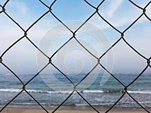Protective mesh on beach background. Sea behind bars. Beach is closed. Swimming is prohibited concept.