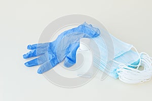 Protective stuff, blue medical mask and glove, white bottle of sanitizer on light background.