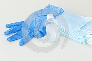 protective stuff, blue medical mask and glove, white bottle of sanitizer on light background.