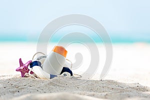 Protective sunscreen or sunblock and sunbath lotion in white plastic bottles with sandals on tropical beach, summer accessories in