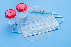 Protective surgical face mask with a syringe and medical containers for biomaterials