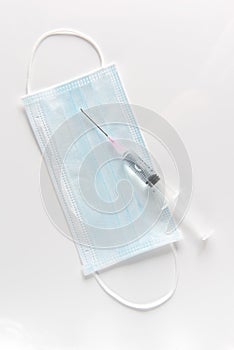 Protective surgical mask, syringe on a white table photo