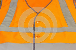 Protective waistcoat in orange with reflective stripes.