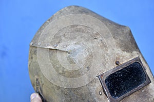 Protective welding shield in hand on a blue background