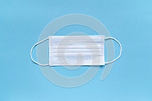 Protective white medical face mask on blue background.