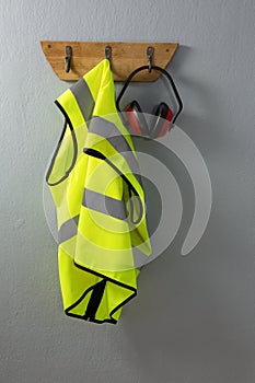 Protective workwear and earmuffs hanging on hook