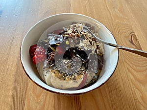 Protein Bowl with Chia Seeds, Banana, Strawberry, Rolled Oats and Bitter Chocolate Pieces on Wooden Table for Breakfast