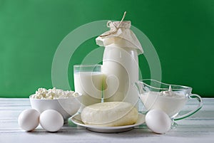 Protein products, a bottle and a glass of milk, sour cream, cottage cheese, eggs, cheese on a white table on an green