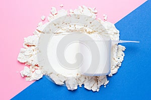 A protein scoop on blue and pink background top view, copy space