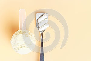 Protein scoop and capsules on a brown background close-up, copy space