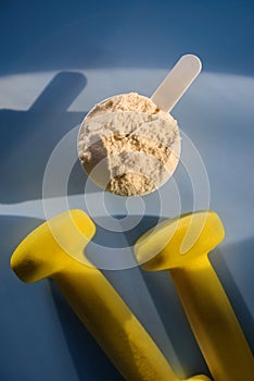 Protein scoop and a pair of dumbbells close-up. The concept of sports nutrition