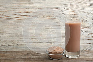 Protein shake and powder on table, space for text