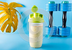 Protein sports shaker. Protein drink and dumbbells. Sports screensaver. Blue background.