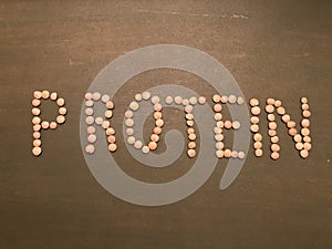 PROTEIN writing with green lentils on green wooden background