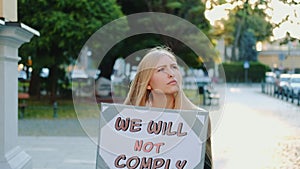 Protest walk: woman holding placard with words that people won`t comply