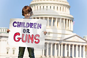 Protester holding sign children or guns in hands photo