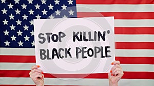 Protester holds a banner with a slogan - Stop killing Black People- against background of the USA flag. Fighting against