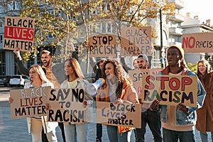 Protesters demonstrating different anti racism slogans outdoors. People holding signs with phrases