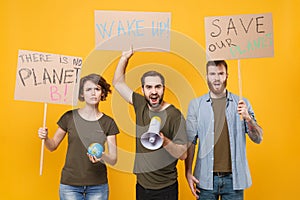 Protesting young people hold protest signs broadsheet placard world globe scream in megaphone isolated on yellow