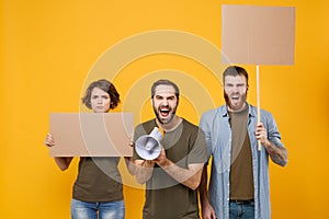 Protesting young three people guys girl hold protest signs broadsheet blank placard on stick screaming in megaphone photo