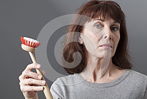 Proud 50s woman handing dish brush for washing and cleaning at home