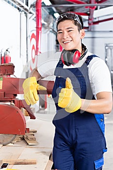 Proud Asian carpenter showing thumbs up