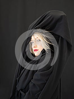 Proud blonde fashion beauty model woman, with red mouth and black fabric, cloth with hair electrostatic charged, sticking to cape