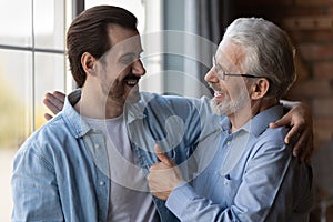 Proud excited elderly dad embrace adult son congratulate with success