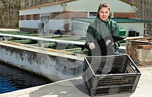 Proud female fish farm owner with sturgeons