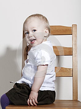 Proud happy baby girl sitting on chair